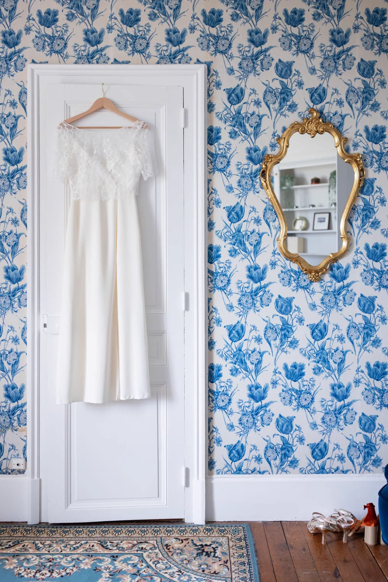 Robe de mariée en dentelle suspendue à une porte, miroir doré