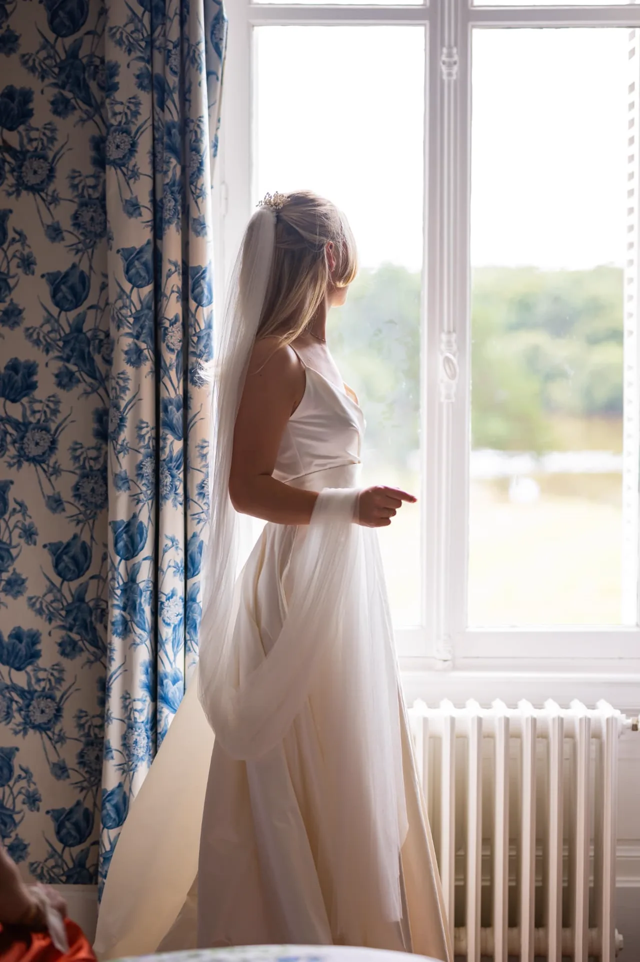 Mariée de dos devant une fenêtre, voile et peigne perlé