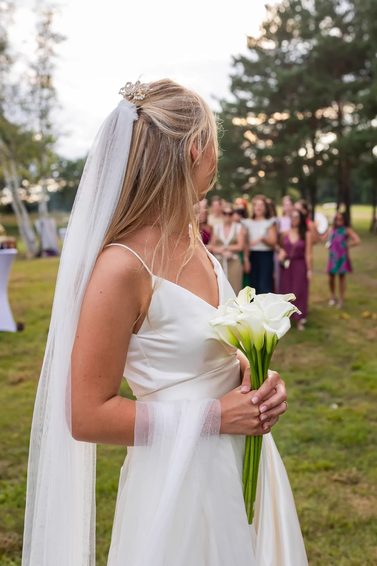 Mariée avec son bouquet d’arums blancs face à ses invités